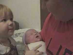 Amy holds baby Esther as Sarah smiles.